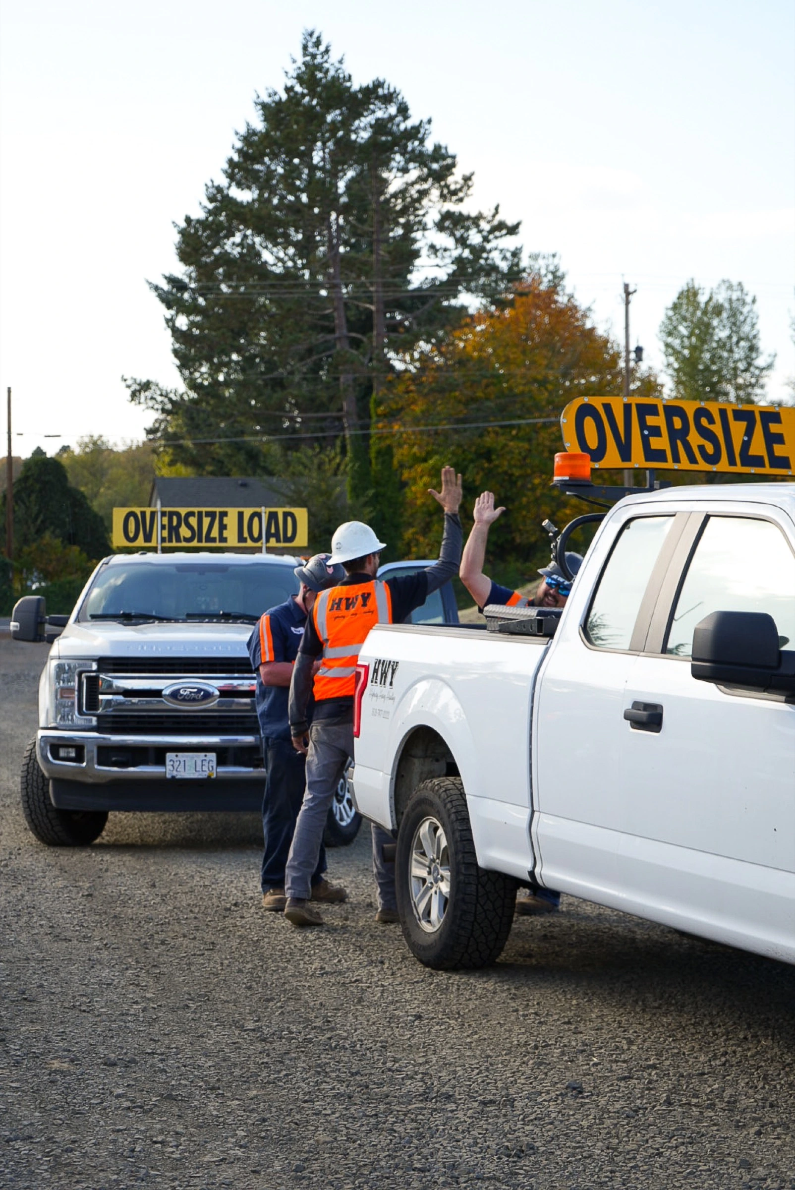 Logistics crew celebrating on site beside oversize load trucks